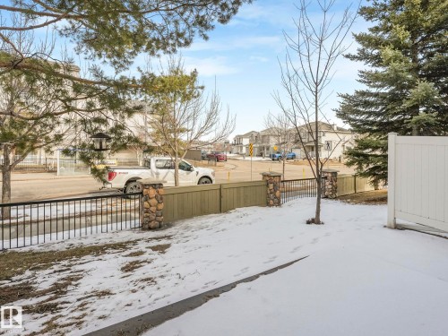 The property features a fenced yard with a combination of wood paneling, black metal railing, and stone pillars - 175 150 Edwards Drive, Edmonton, AB - Outdoor