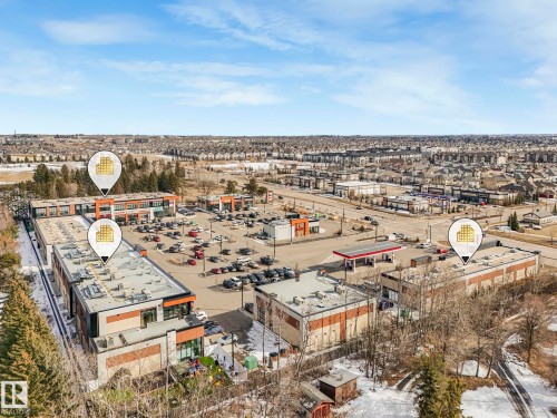 Aerial view of a commercial property featuring a parking lot, multiple buildings, and a gas station - 175 150 Edwards Drive, Edmonton, AB - Outdoor With View