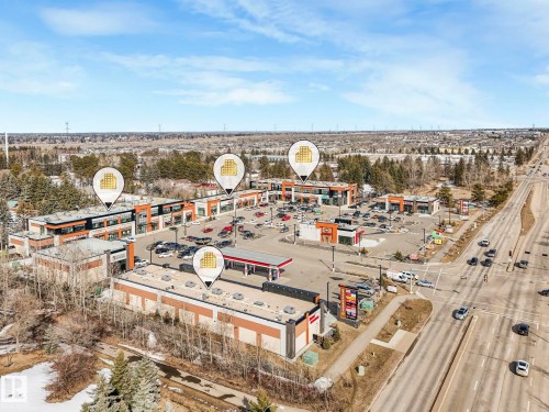 Aerial view showcasing the property's commercial buildings, ample parking areas, and proximity to a major road - 175 150 Edwards Drive, Edmonton, AB - Outdoor With View