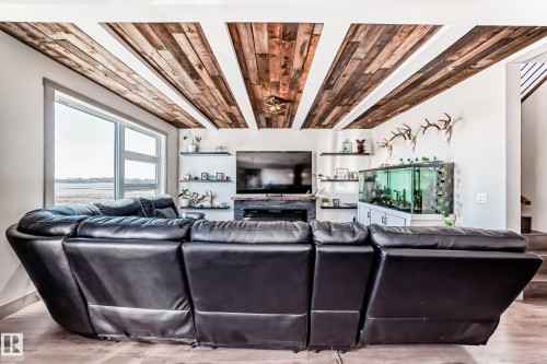 Living area featuring a wood-panel ceiling, built-in fireplace, and expansive windows - 5263 47 Ave, Calmar, AB - Indoor Photo Showing Living Room With Fireplace