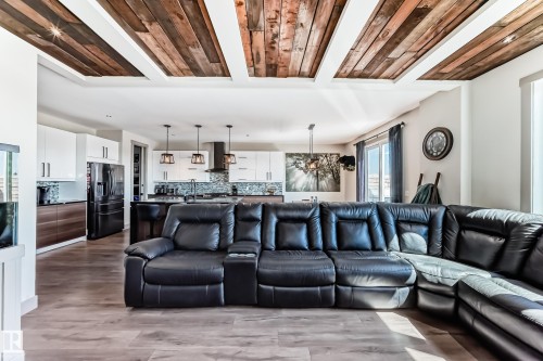 Open-concept living area with wood-finish flooring and a coffered ceiling featuring wood plank accents - 5263 47 Ave, Calmar, AB - Indoor Photo Showing Living Room
