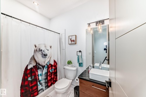 Modern bathroom featuring a contemporary vanity with a rectangular vessel sink, dark countertop, and wood-finish cabinetry - 5263 47 Ave, Calmar, AB - Indoor Photo Showing Bathroom