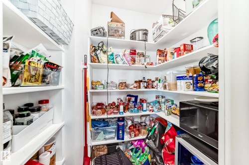 Spacious pantry featuring multiple tiers of white shelving, built-in microwave, and ample storage solutions - 5263 47 Ave, Calmar, AB - Indoor With Storage