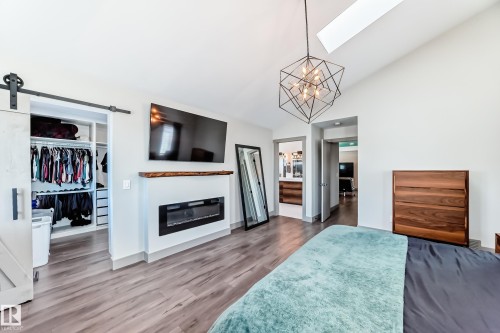 Vaulted ceilings with a geometric pendant light fixture and skylight - 5263 47 Ave, Calmar, AB - Indoor Photo Showing Bedroom With Fireplace