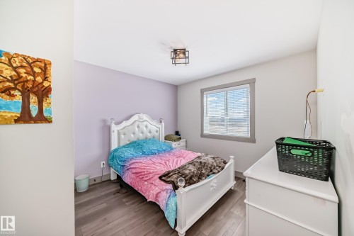 Light-filled room featuring wood-finish flooring, a window with blinds and gray trim, and a ceiling-mounted light fixture - 5263 47 Ave, Calmar, AB - Indoor Photo Showing Bedroom