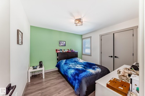 Spacious room featuring wood-finish flooring, a contemporary ceiling light fixture, and a window with blinds - 5263 47 Ave, Calmar, AB - Indoor Photo Showing Bedroom
