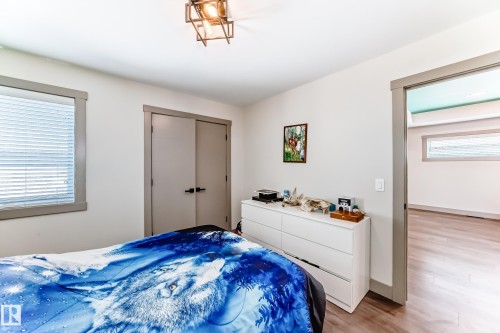 Room featuring a window with blinds, wood-finish flooring, and a modern geometric ceiling light fixture - 5263 47 Ave, Calmar, AB - Indoor Photo Showing Bedroom