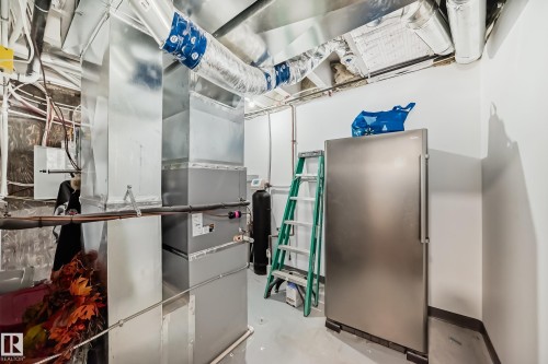 Utility area featuring exposed ductwork, white walls, and a stainless steel refrigerator - 5263 47 Ave, Calmar, AB - Indoor