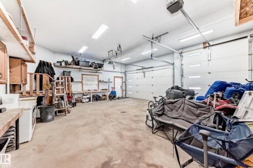 Spacious garage with two overhead doors, concrete flooring, overhead fluorescent lighting, and built-in shelving - 5263 47 Ave, Calmar, AB - Indoor Photo Showing Garage