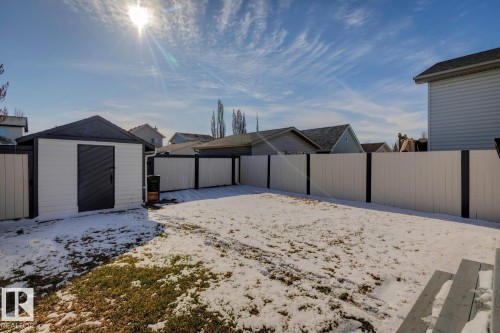 Private backyard featuring a well-maintained shed with a dark roof and door, complemented by a white and dark-accented perimeter fence - 15043 132 Street, Edmonton, AB - Outdoor With Exterior