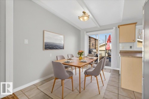 Dining area featuring ceramic tile flooring, a coffered ceiling, and a sliding glass door leading to an outdoor deck - 13508 81 Street, Edmonton, AB - Indoor Photo Showing Dining Room