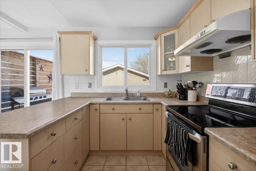 Kitchen featuring wood-finish cabinetry, laminate countertops, a tile backsplash, and a ceramic tile floor - 13508 81 Street, Edmonton, AB - Indoor Photo Showing Kitchen With Double Sink