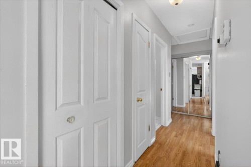 Corridor featuring wood-finish flooring, white panel doors, and mirrored closet doors - 13508 81 Street, Edmonton, AB - Indoor Photo Showing Other Room