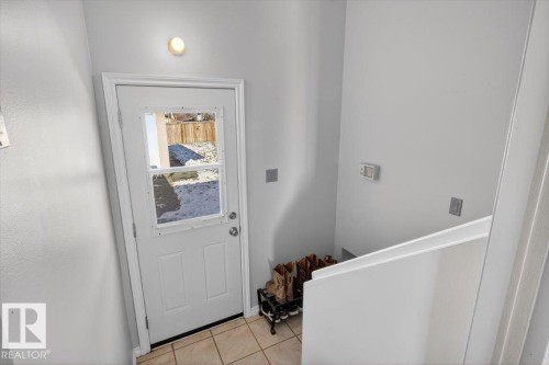 Rear entry door with integrated window panels, ceramic tile flooring, and a contemporary wall light fixture - 13508 81 Street, Edmonton, AB - Indoor Photo Showing Other Room