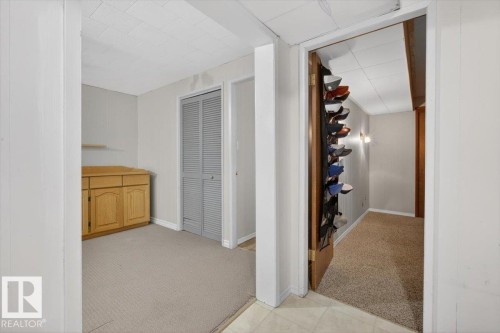 Carpeted room with a built-in wood-finish cabinet, wall shelving, and bi-fold louvered doors - 13508 81 Street, Edmonton, AB - Indoor Photo Showing Other Room