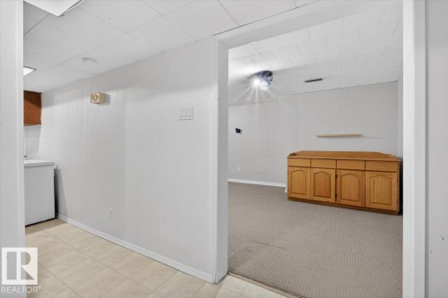 Interior space featuring a built-in wood-finish cabinet with four doors and four drawers, complemented by a floating shelf - 13508 81 Street, Edmonton, AB - Indoor Photo Showing Other Room