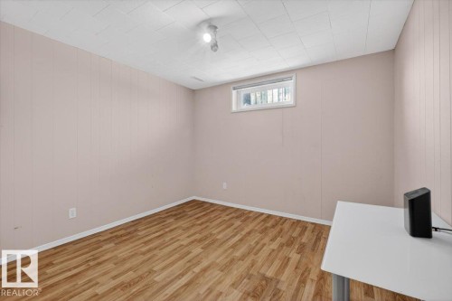 Room featuring wood-finish flooring, light-toned paneled walls, and a white grid-patterned ceiling - 13508 81 Street, Edmonton, AB - Indoor Photo Showing Other Room