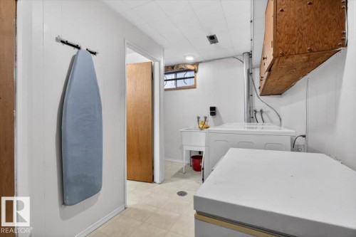 Utility area featuring white panel walls, wood-finish cabinetry, and a utility sink - 13508 81 Street, Edmonton, AB - Indoor Photo Showing Laundry Room