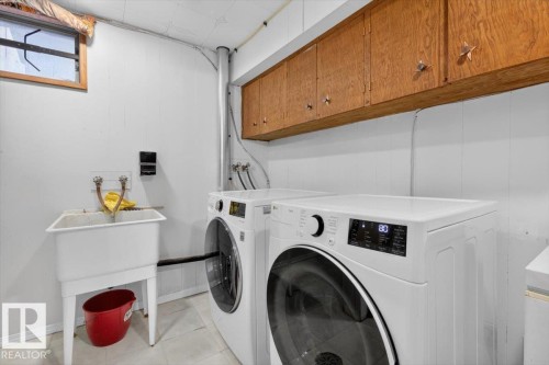 Dedicated laundry area featuring a utility sink, overhead wood-finish cabinetry, and paneling on the walls - 13508 81 Street, Edmonton, AB - Indoor Photo Showing Laundry Room