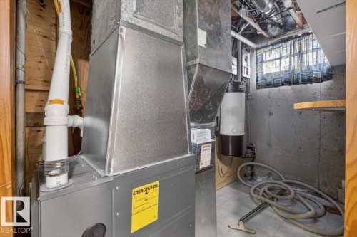 HVAC system with visible ductwork, a water heater, concrete foundation walls, a window with patterned curtains, and an exposed wood ceiling frame - 13508 81 Street, Edmonton, AB - Indoor Photo Showing Basement