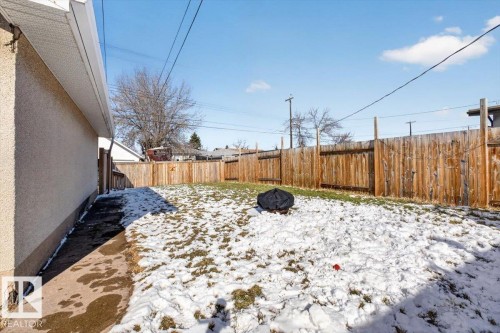 Fenced backyard featuring a stucco exterior, concrete walkway, and wood fencing - 13508 81 Street, Edmonton, AB - Outdoor