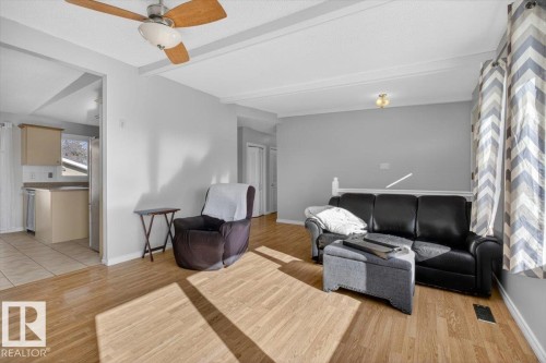Living area featuring wood-finish flooring, a ceiling fan with integrated lighting, and crown molding accents - 13508 81 Street, Edmonton, AB - Indoor