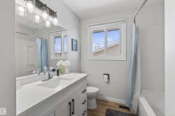 Bathroom featuring a white vanity with black hardware, a rectangular undermount sink, and a single-handle chrome faucet - 