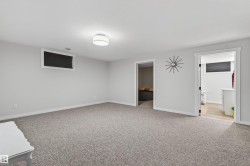 Spacious room with light gray walls, textured gray carpeting, white trim, and a flush-mount ceiling light - 