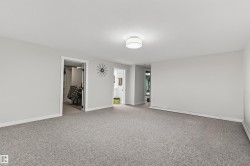 Spacious room featuring neutral carpeting, white baseboards, and a contemporary flush-mount ceiling light fixture - 