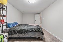 Room featuring neutral wall tones, carpet flooring, a white paneled door with dark hardware, and overhead flush-mount lighting - 