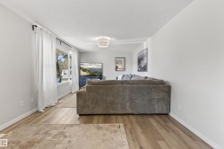Bright living area featuring wood-finish flooring, a large window with white trim, and a contemporary ceiling fixture - 