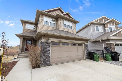 Two-story residence featuring composite siding, stacked stone accents, an attached two-car garage with transom windows, a concrete driveway, and a covered front entry - 1586 Chapman Way, Edmonton, AB - Outdoor With Facade