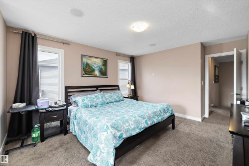 Carpeted room featuring neutral wall tones, two windows with white trim, and a ceiling-mounted light fixture - 1586 Chapman Way, Edmonton, AB - Indoor Photo Showing Bedroom