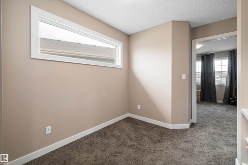 Textured carpeting and neutral wall tones feature in this room, complete with a horizontal window and white trim - 1586 Chapman Way, Edmonton, AB - Indoor Photo Showing Other Room