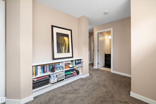 Built-in shelving unit with a white finish, neutral wall paint, white trim, and textured carpeting - 1586 Chapman Way, Edmonton, AB - Indoor Photo Showing Other Room