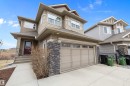 Two-story residence featuring a two-car garage with transom windows, a dark red front door, and natural stone veneer accents - 1586 Chapman Way, Edmonton, AB  - Outdoor 