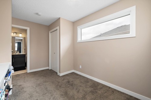 Carpeted room featuring a horizontal transom window, neutral wall paint, white trim, and a bi-fold closet door - 1586 Chapman Way, Edmonton, AB - Indoor Photo Showing Other Room