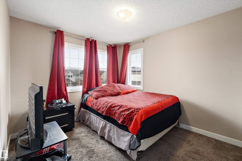 Bedroom featuring three windows with white frames, neutral wall paint, and textured carpeting - 1586 Chapman Way, Edmonton, AB - Indoor Photo Showing Bedroom