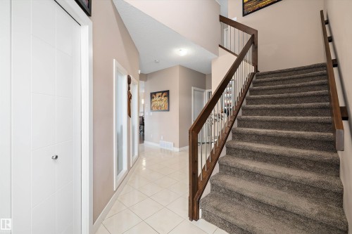 Carpeted staircase with dark wood handrails and white balusters - 1586 Chapman Way, Edmonton, AB - Indoor Photo Showing Other Room