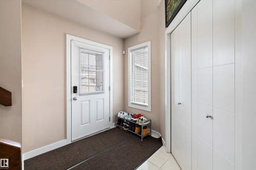 Entryway featuring a white door with an integrated window, a side window with blinds, and a built-in closet with panel doors and chrome hardware - 1586 Chapman Way, Edmonton, AB - Indoor Photo Showing Other Room