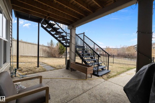 Concrete patio with an overhead deck, featuring a black metal staircase and railing - 1586 Chapman Way, Edmonton, AB - Outdoor With Exterior