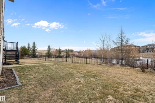 Expansive backyard featuring a wrought iron fence, concrete pathway, and a waterside setting - 1586 Chapman Way, Edmonton, AB - Outdoor With View