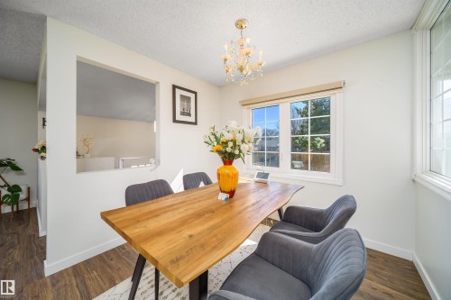 Dining area featuring wood-finish flooring, white baseboards, and a pass-through window opening - 5303 21 Avenue, Edmonton, AB - Indoor Photo Showing Dining Room