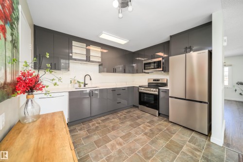 Contemporary kitchen featuring gray flat-panel cabinetry, stainless steel appliances, white countertops, a mosaic tile backsplash, and a modern black faucet - 5303 21 Avenue, Edmonton, AB - Indoor Photo Showing Kitchen With Upgraded Kitchen