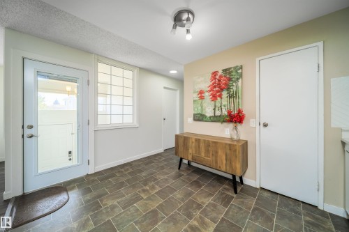Entryway featuring dark rectangular floor tiles set in a diagonal pattern, a full-lite exterior door with chrome hardware, and an interior window with grid details - 5303 21 Avenue, Edmonton, AB - Indoor Photo Showing Other Room