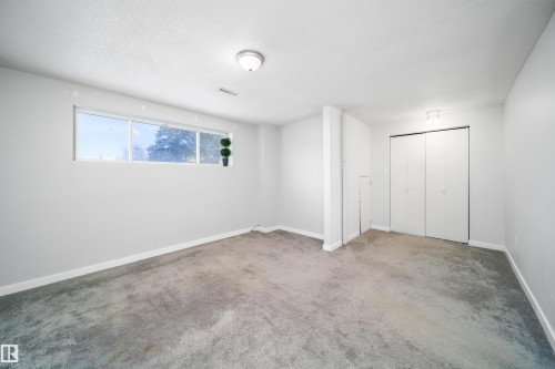 Spacious room with light gray walls, gray carpeting, and a horizontal window - 5303 21 Avenue, Edmonton, AB - Indoor Photo Showing Other Room