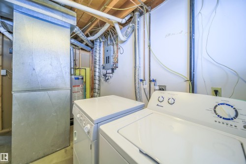 Dedicated laundry area featuring a top-loading washing machine and a front-loading dryer, alongside exposed ductwork and utility connections - 5303 21 Avenue, Edmonton, AB - Indoor Photo Showing Laundry Room