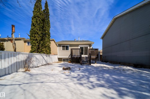 Spacious backyard featuring a white picket fence, large wooden deck with stairs, siding exterior, and a visible basement window - 5303 21 Avenue, Edmonton, AB - Outdoor