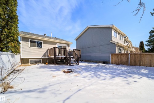 Rear exterior featuring a spacious deck with stairs, a ground-level patio door, and a privacy fence - 5303 21 Avenue, Edmonton, AB - Outdoor With Exterior