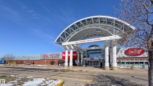 Commercial building featuring a prominent arched entrance canopy, extensive glass storefronts, and brick exterior walls - 5303 21 Avenue, Edmonton, AB - Outdoor